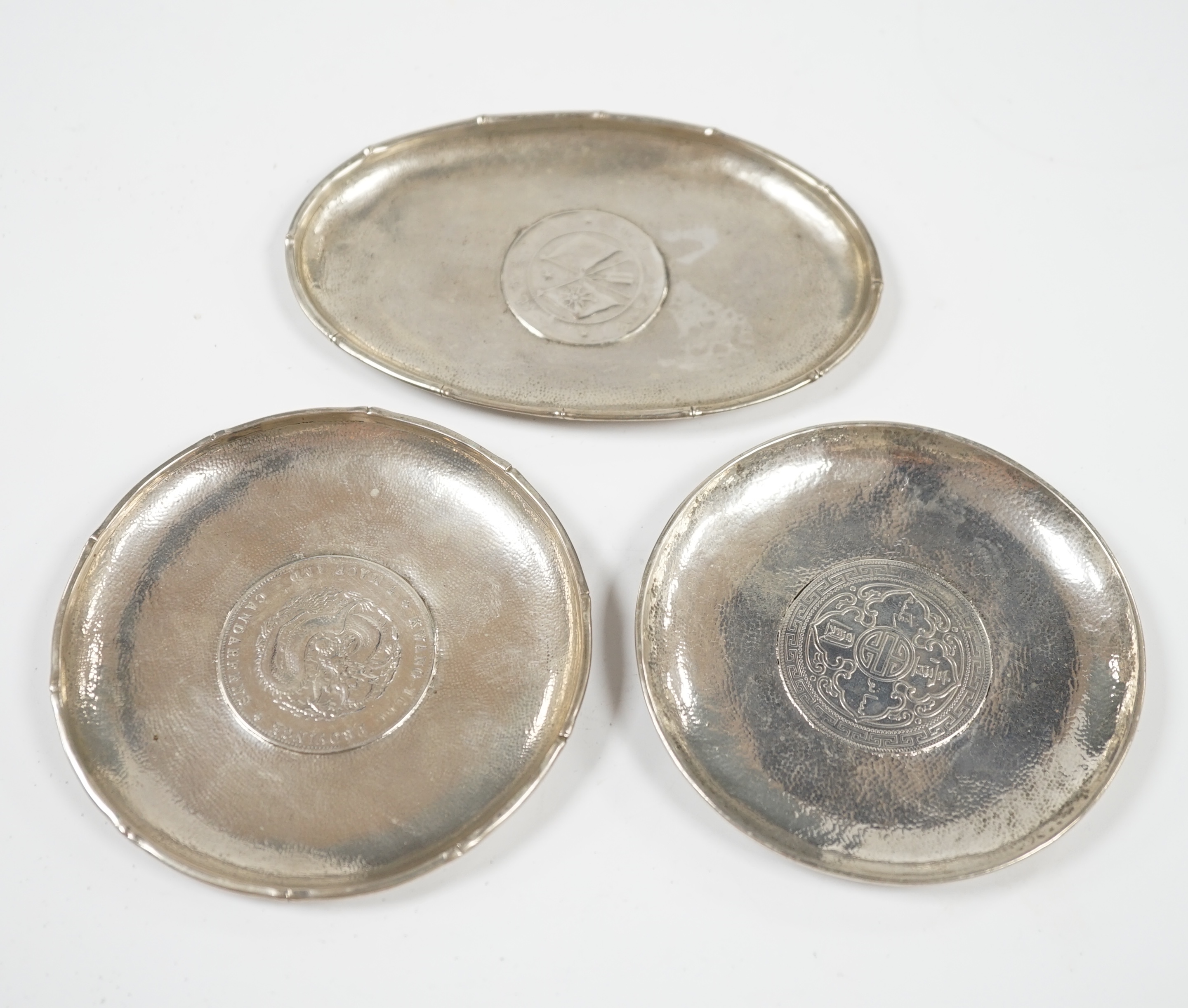 Three assorted small Chinese white metal dish, each inset with a coin, largest 11.8cm. Condition - fair